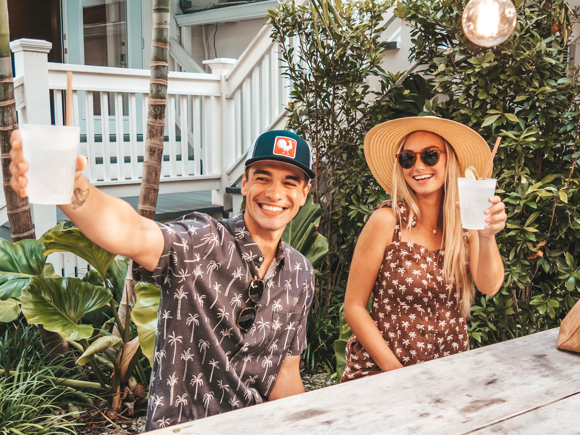 a couple sitting at a wooden table outdoors enjoying a refreshment