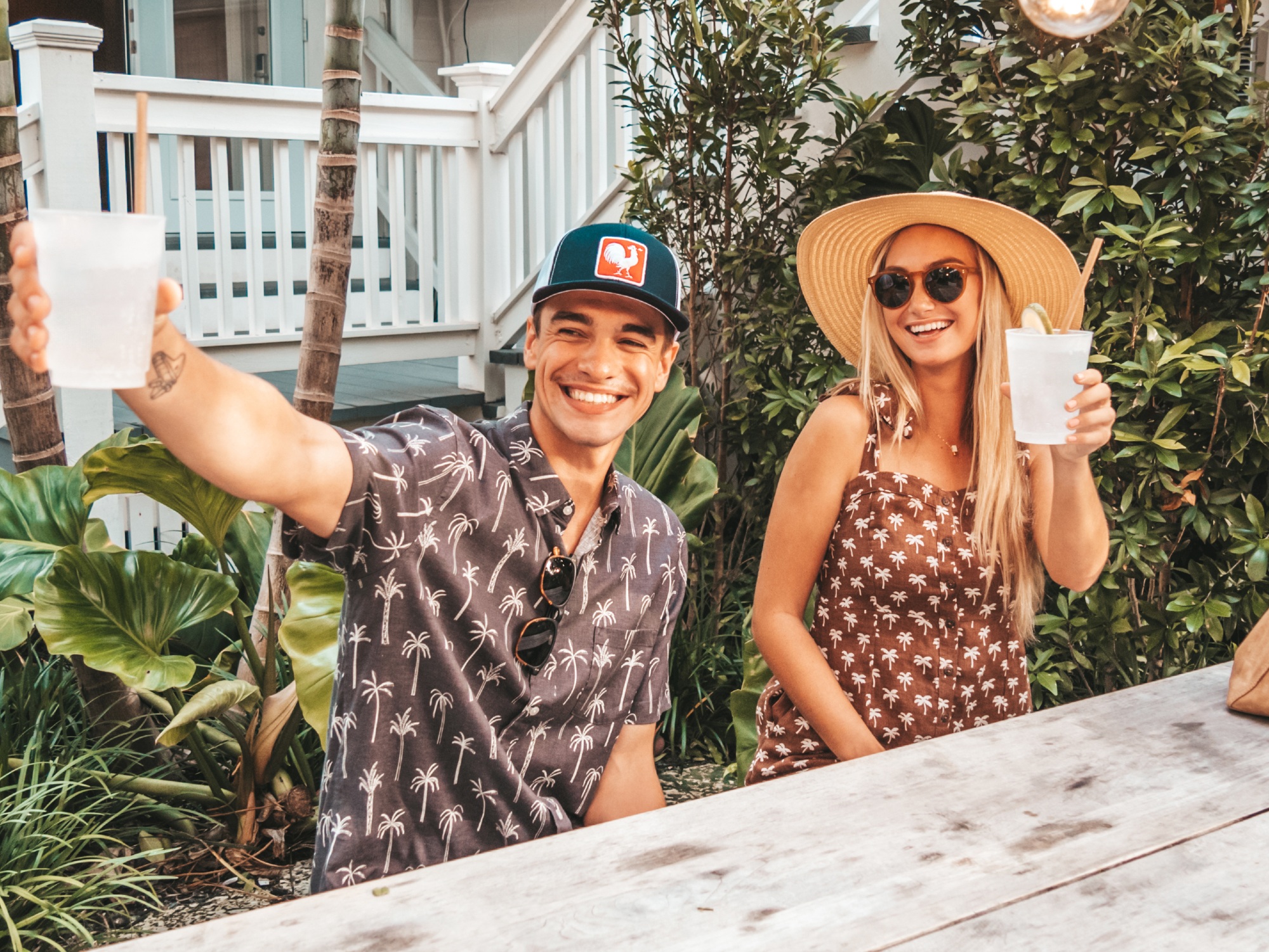 a couple sitting at a wooden table outdoors enjoying a refreshment