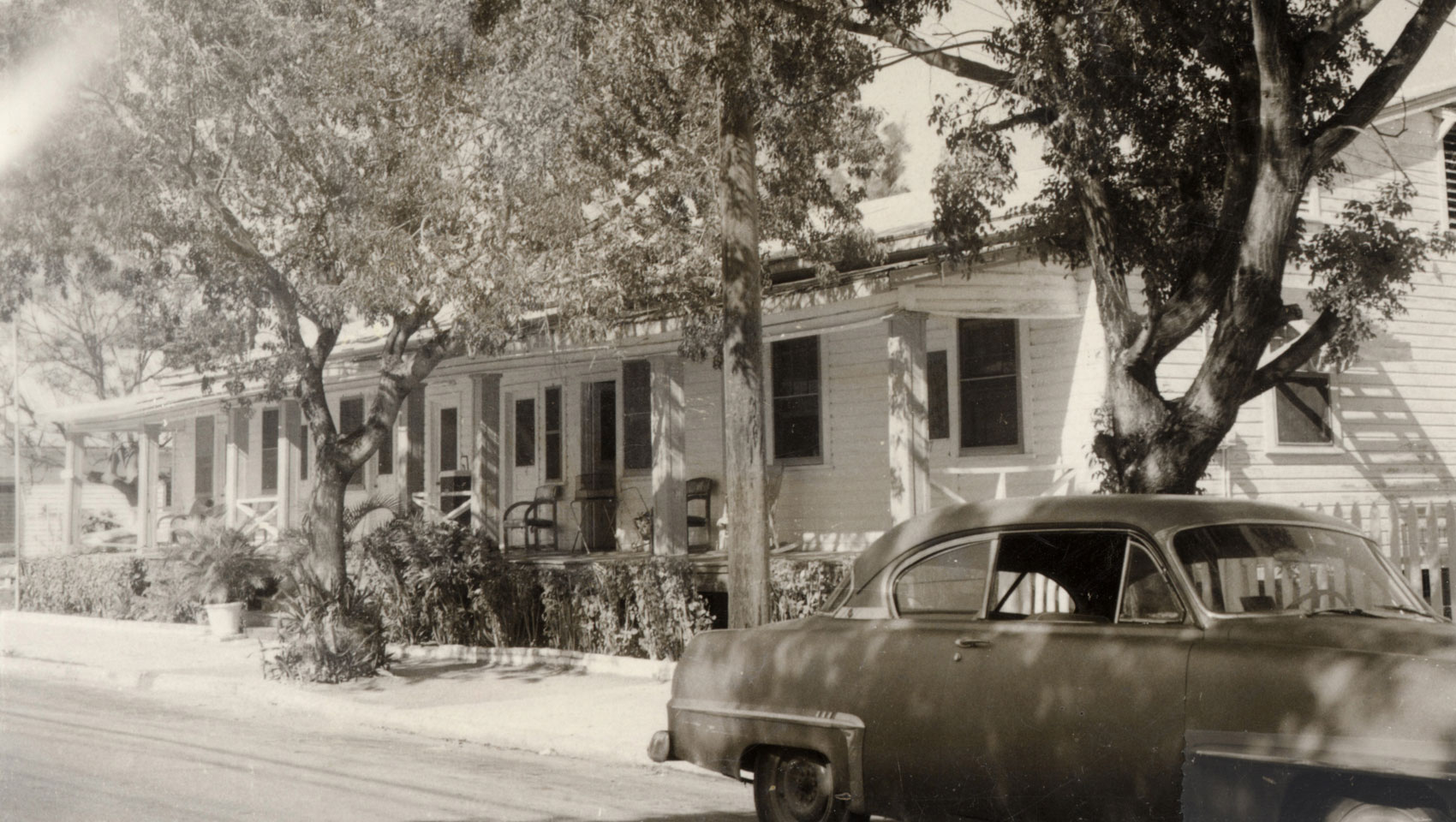 A historic photo of the Merlin Hotel with an antique car parked out front.